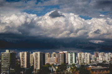 Obraz premium Beautiful and scenic sunlight and cloudy sky over Santiago skyline, Santa Lucía hill and the snowed The Andes Mountains, Chile
