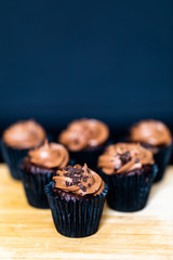 Chocolate cupcakes with shallow depth of field and dark background sitting on a wooden board