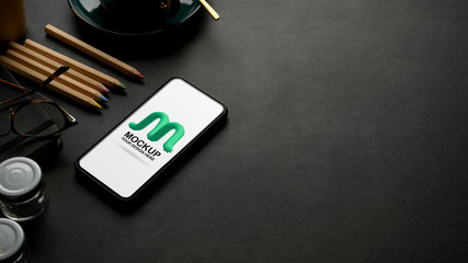 Cropped shot of mock up smartphone on black leather worktable