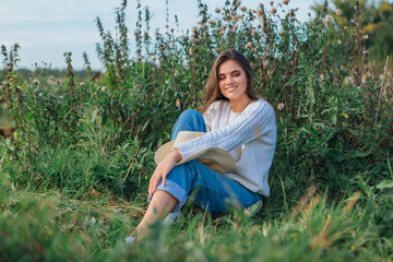 Young beautiful brunette woman sitting on the grass and smiling