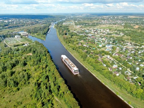 Aerial view journey by passenger cruise ship on the river. Beautiful panoramic landscape from a height ship sails along a large river against the background of water and clouds