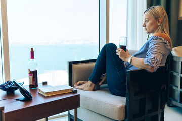 Young Woman reading with a glass of win and mobile phone charging on cordless charging device