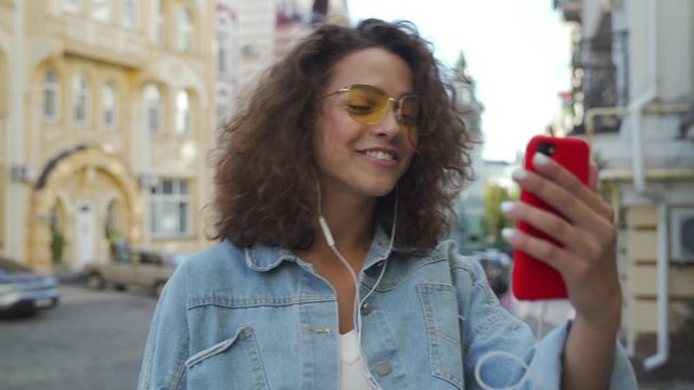 Young beautiful latin girl laughing while making a video call on her smartphone.
