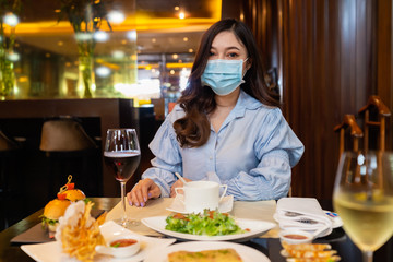 woman wearing medical mask for prevent to coronavirus (covid-19) in restaurant, new normal concept