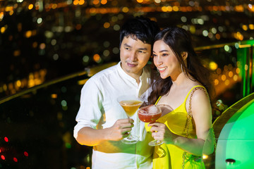 couple in nightclub with cocktails over night city background
