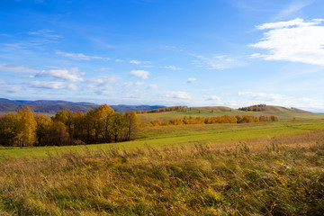 Landscape panorama of a hilly area with autumn colors and blue sky.