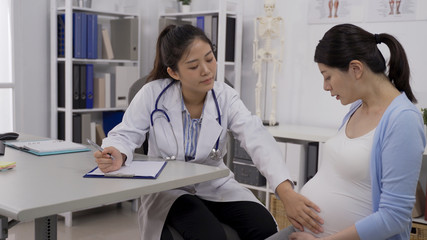 determine the height of the fundus of the uterus. korean female gynecologist palpating pregnant...