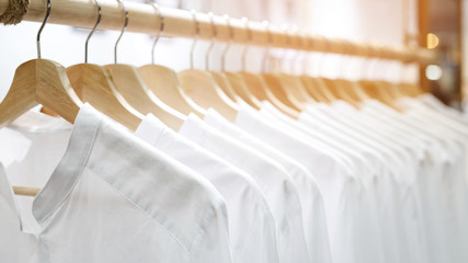 Female clothes shirts white on rail hanging on hangers.