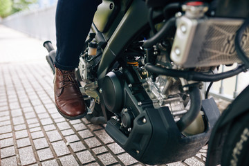 Plakat Close-up image of motorcyclist in leather shoes pushing pedal to start riding