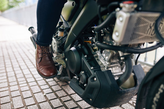 Close-up image of motorcyclist in leather shoes pushing pedal to start riding