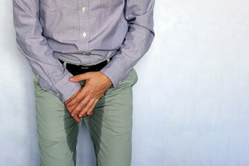 adult man holds hands the groin area and trousers wet from urine. Urinary incontinence concept. Wet...