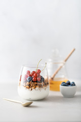 Breakfast, granola with yogurt and berries in a jar on a light background
