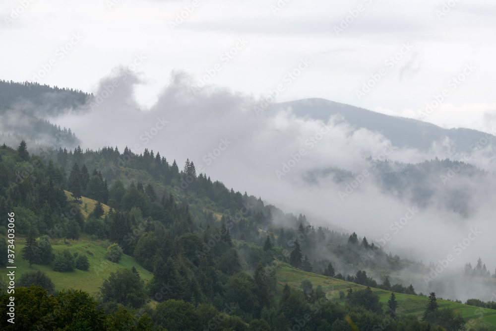 Sticker Majestic view on beautiful fog and cloud mountains in mist landscape.