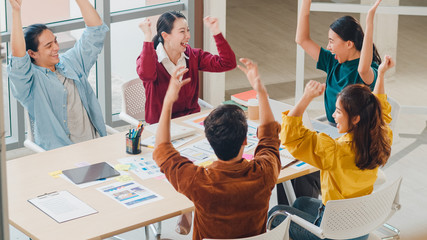 Multiracial group of young creative people in smart casual wear discussing business gesture hand high five, laughing and smiling together in brainstorm meeting at office. Coworker teamwork concept.