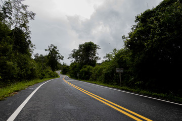 Logistic concept aerial view of countryside road - motorway passing through the serene lush greenery and foliage tropical rain forest mountain landscape
