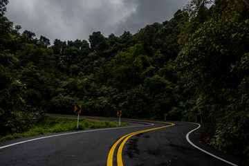 Logistic concept aerial view of countryside road - motorway passing through the serene lush greenery and foliage tropical rain forest mountain landscape