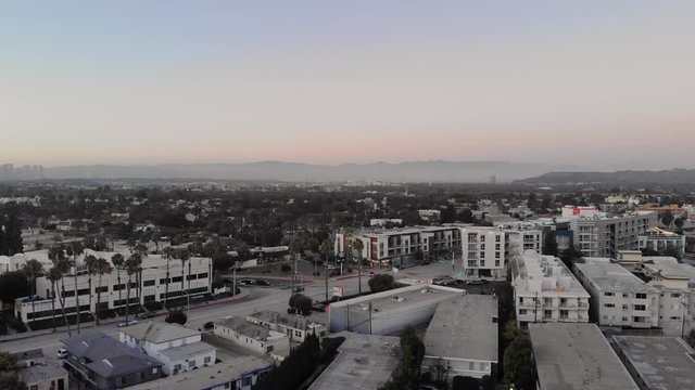 Aerial, evening drone shot flying over streets of the Culver city neighborhood with mountains in background, in Los Angeles, California, USA