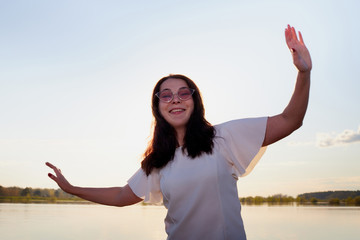 Portrait of the girl or woman on the shore or beach of the lake in the evening at sunset.
