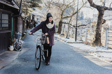 Traveler woman with bicycle on the road in Japan, winter.