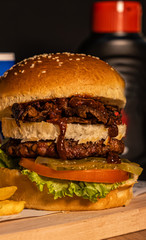 Triple burger bread. Meat doner, hamburger with meatballs and French fries. Black background and wooden floor. With tomato, lettuce, pickles