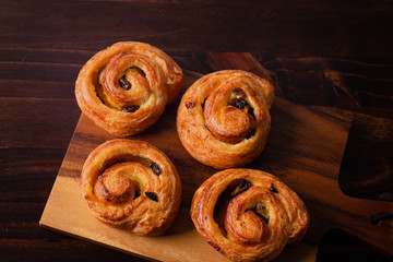puff pastry cinnamon rolls with custard and raisins dark  wooden background. Top view, space.