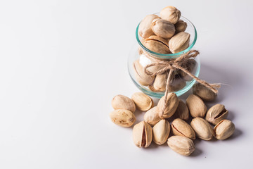 Pistachios in glass bottles on white background. Copy space.