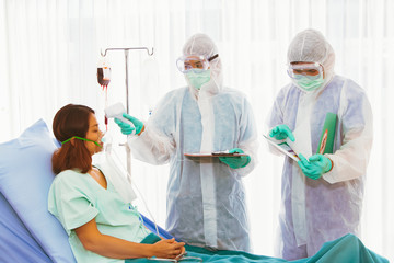 Medical team used a thermometer. Infrared fever measurement and note taking, closely monitor symptoms, while treating patients with coronavirus infection. In a hospital quarantine room