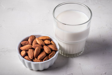 Close up. Almonds in a white ceramic cup and a milk glass.
