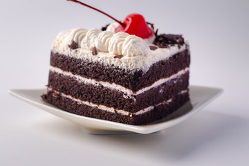 Chocolate layer cake with cherries on top on white background