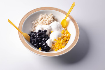 Thai style coconut milk ice cream with topping on the side on a white background