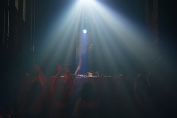Fototapeta na wymiar DJ and crowd of dancing people in nightclub