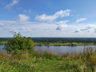 green banks of the river against the background of a beautiful blue sky with clouds