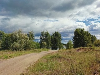 Fototapeta na wymiar country road with trees and cloudy stormy sky