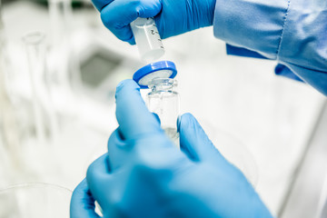 Flask and pipette in scientist hand with dropping chemical liquid to test tubes, science and medical research and development concept