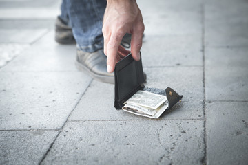 Caucasian man picking up a lost wallet in a city.