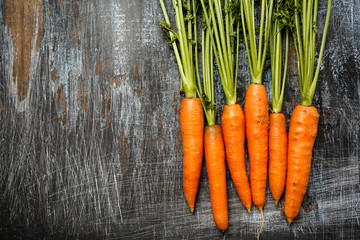 Young fresh organic farmer carrots on rustic background, top view