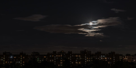 Moon in the night sky in a big city