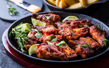 Roasted chicken wings in barbecue sauce with lime and baked potatoes