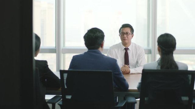 nervous mature asian business man being interviewed by a group of HR executives in office of modern company