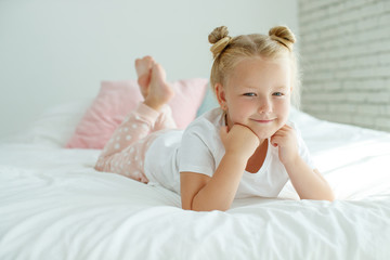 Little girl in bed with white linen. A child at home in the morning wakes up in his room. High quality photo.