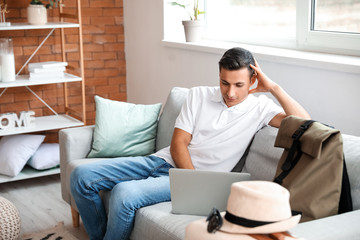 Man with laptop booking tickets online at home