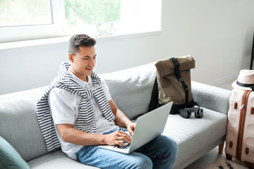 Man with laptop booking tickets online at home