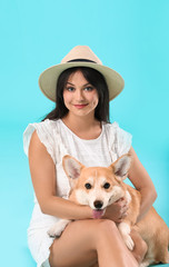 Woman with cute corgi dog on color background