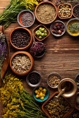 Natural medicine background. Assorted dry herbs in bowls and brass mortar on rustic wooden table.
