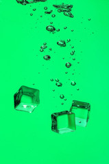 Falling of ice cubes into water on color background