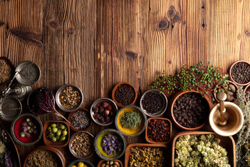 Natural medicine background. Assorted dry herbs in bowls and brass mortar on rustic wooden table.