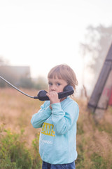 A girl calls an old wired street phone in the middle of a village .