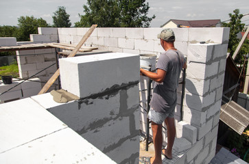 A worker builds the walls of a house from aerated concrete bricks.