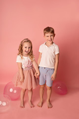 Happy child girl and boy on a pink background with balloons. Celebration. birthday