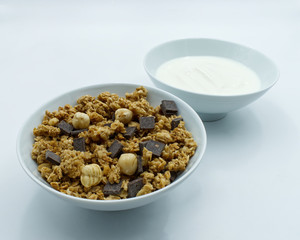Bowl of mixed Muesli and a cup of white yogurt isolated on white background